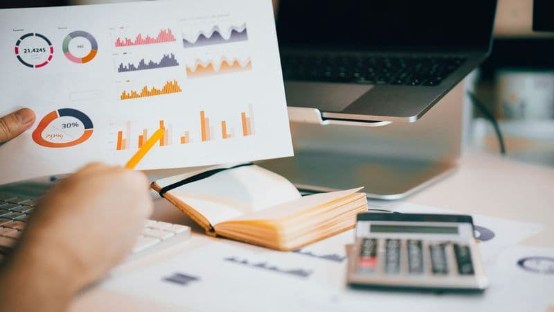 Analyst reviewing printed performance data against a laptop during a marketing attribution audit
