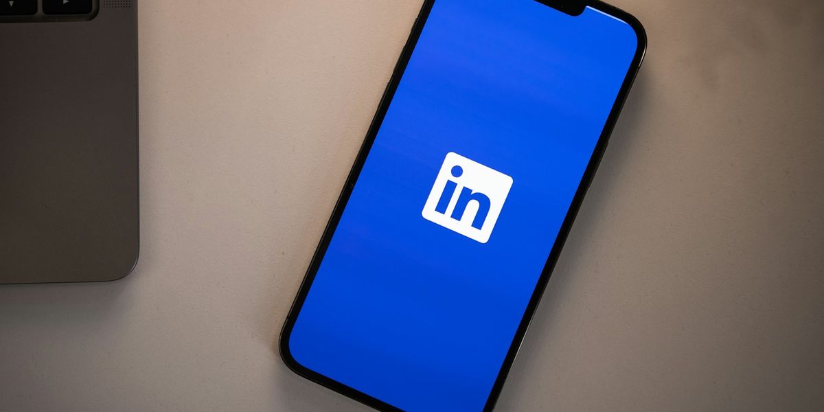 A smartphone displaying the LinkedIn logo on a bright blue screen on a desk