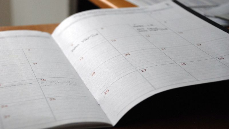 Open monthly paper planner on a wooden desk, used for mapping a content distribution calendar