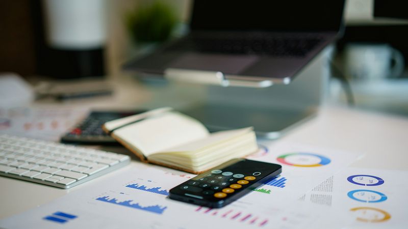 Desk with printed financial charts and a smartphone, representing B2B marketing budget planning