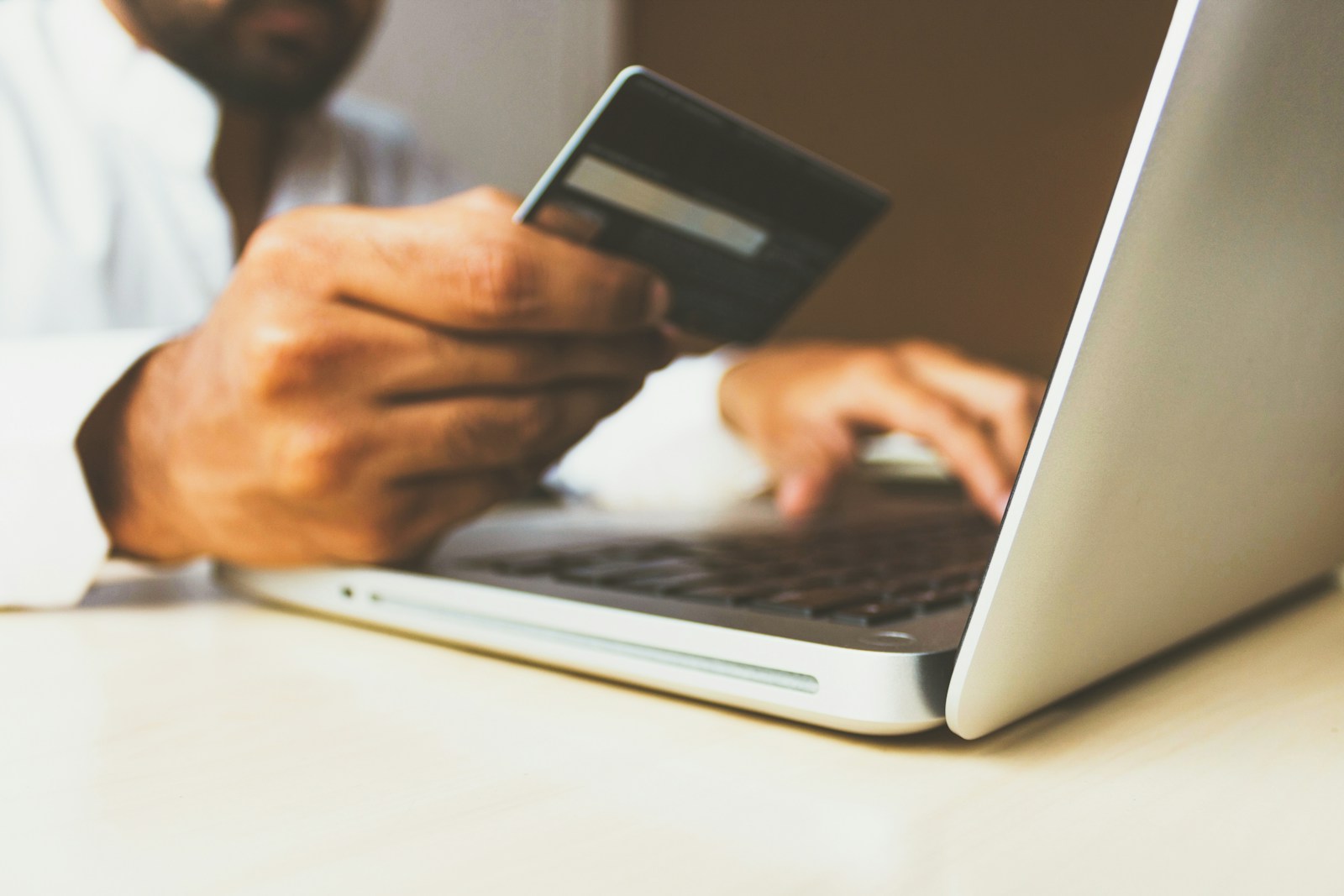 Person using a laptop and holding a payment card